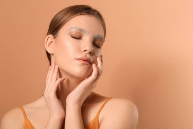 Renkli arka planda boyalı kaşları olan güzel bir genç kadın.