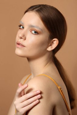 Renkli arka planda boyalı kaşları olan güzel bir genç kadın.