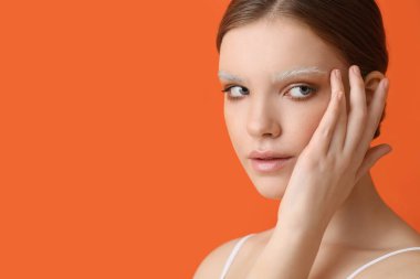 Renkli arka planda boyalı kaşları olan güzel bir genç kadın.