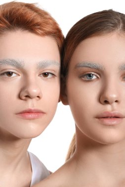 Beyaz arka planda boyalı kaşları olan gençler, yakın plan.