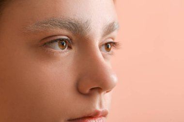 Renkli arka planda boyalı kaşları olan genç çocuk, yakın plan.