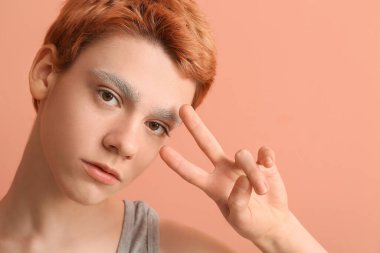 Kaşları boyalı ergen çocuk renk geçmişinde zafer jesti gösteriyor.