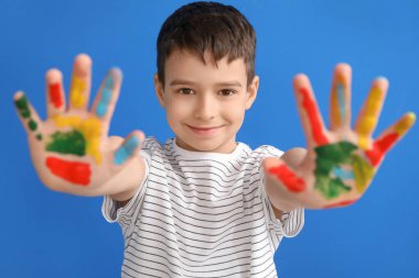 Renkli arka planda elleri boyalı küçük bir çocuk.