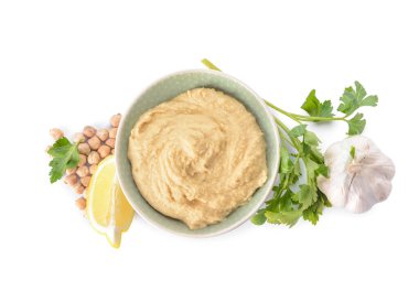 Lezzetli humus ve beyaz arka planda malzemelerle dolu bir kase.