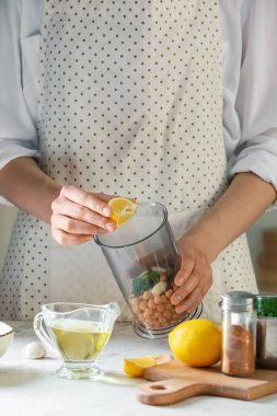 Mutfaktaki masada bezelyeyle limonu karıştıran kadın, yakın plan.