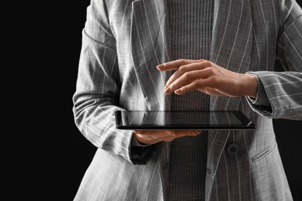Koyu arkaplanda tablet bilgisayar kullanan genç bir kadın