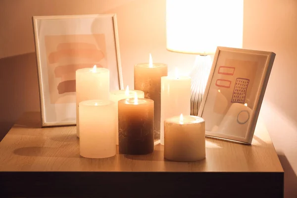 Burning candles with pictures on table in room