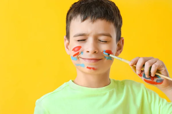 Kleiner Junge Mit Pinsel Und Gesicht Auf Farbigem Hintergrund — Stockfoto