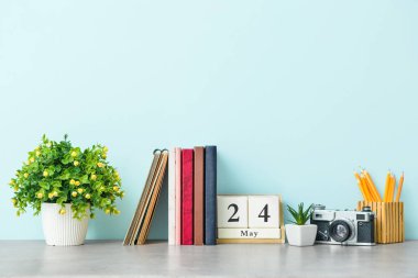 Renkli duvarın yanında fotoğraf makinesi, not defteri ve kırtasiye malzemesi olan şık bir iş yeri