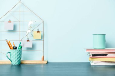 Renk duvarının yanında not defterleri ve kırtasiye malzemesi olan şık bir iş yeri