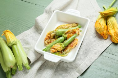 Ahşap arka planda kızarmış kabak çiçekli fırın tabağı.