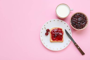 Lezzetli kiraz reçelli sandviç ve renkli arka planda bir fincan süt.