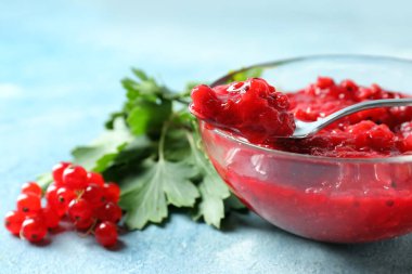 Kase lezzetli kırmızı frenk üzümü reçeli, renkli arka planda böğürtlen ve yapraklar, yakın plan