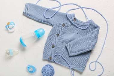 Aksesuarlı şık bebek kıyafetleri ve beyaz arka planda örgü ipliği.