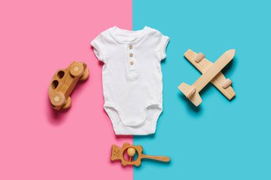 Stylish baby clothes with toys on color background clipart
