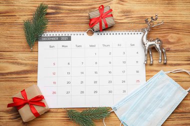 Ahşap arka planda Noel dekoru ve tıbbi maskeli takvim