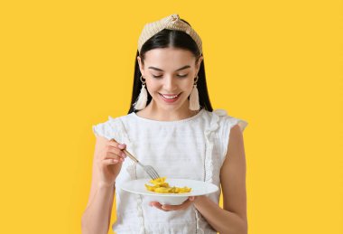 Renkli arkaplanda lezzetli ravioli yiyen güzel genç bir kadın.