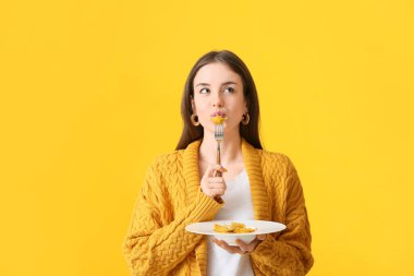 Renkli arkaplanda lezzetli ravioli yiyen güzel genç bir kadın.