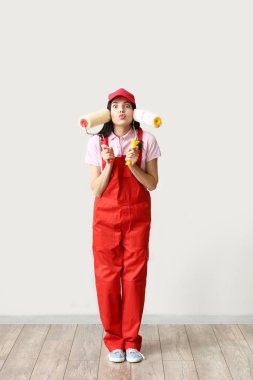 Işık duvarının yanında boya ruloları olan komik bir kadın dekoratör.