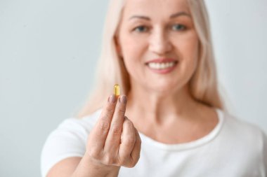 Açık arkaplanda balık yağı olan olgun bir kadın.