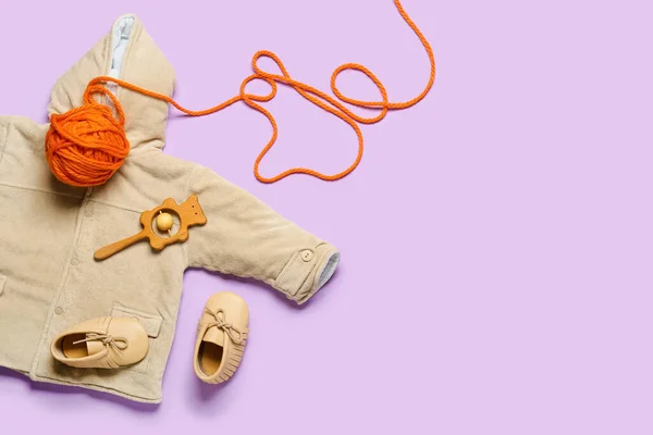 Stylish baby clothes with toy and knitting yarn on color background