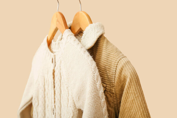 Стильная детская одежда на вешалках на цветном фоне