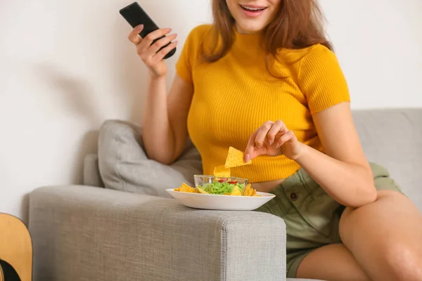 Beautiful Young Woman Eating Tasty Nachos While Watching Home — Stock Photo, Image