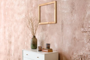 Vazolu mumlar ve renkli duvarın yanındaki raflarda kitaplar.