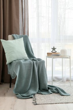 Ekoseli sandalye ve ışık perdelerinin yanındaki masa.