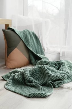 Dinlenmek için rahat bir yer. Yastık ve pencerenin yanında ekose kumaş örülmüş.