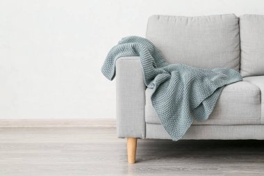 Işık duvarının yanında örülmüş ekose kanepe.