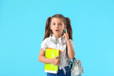 Renkli arka planda işaret parmağı kaldırmış şirin küçük okul kızı.