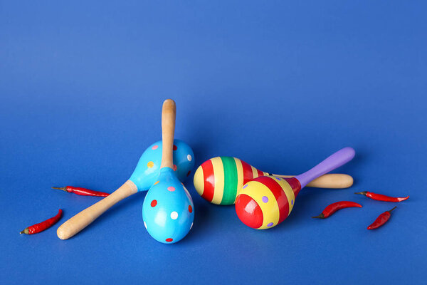 Мексиканские маракасы и перец чили на цветном фоне