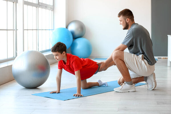 Физиотерапевт, работающий с мальчиком в реабилитационном центре