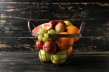 Koyu ahşap arka planda taze meyve dolu sepet.