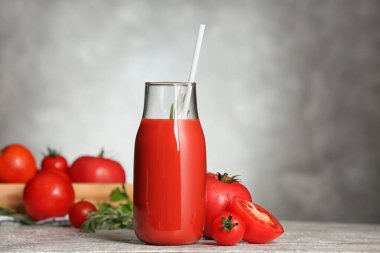 Gri arkaplanda bir şişe lezzetli domates suyu.