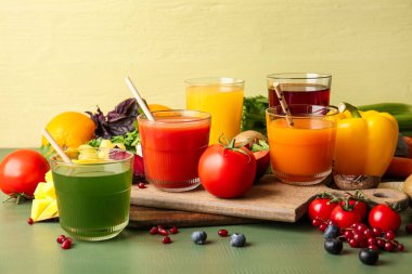 Sağlıklı meyve suyu, meyveler ve sebzeler renkli ahşap arka planda.