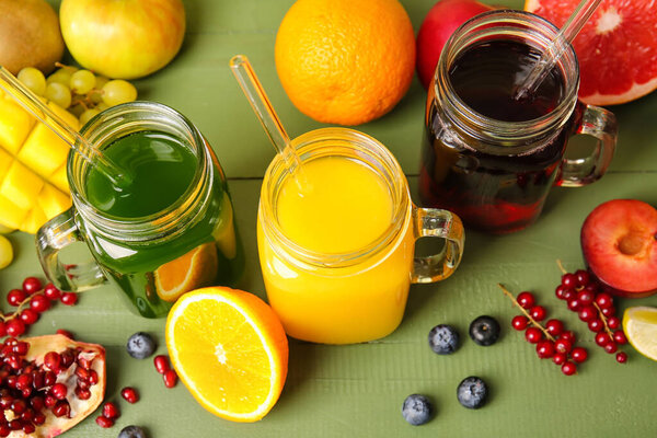 Масонские банки со здоровым соком, фрукты и овощи на цветном деревянном фоне