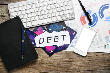 Sözcüklü kağıt, kredi kartları ve ahşap arka planda cihazlar.