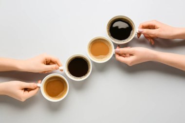 Kadın eli ve kahve fincanları açık arkaplanda.