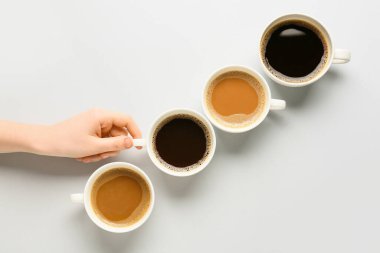 Kadın eli ve kahve fincanları açık arkaplanda.