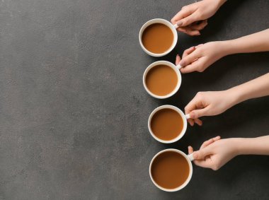 Kadın eli ve kahve fincanları koyu arkaplanda.