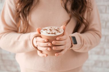 Evde bir fincan kahveyle genç bir kadın, yakın plan.