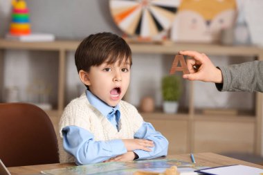 Küçük çocuk konuşma terapisti ofisinde A harfini telaffuz ediyor.