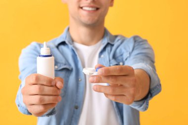 Kontakt lensleri ve solüsyonu olan genç adam, yakın plan.