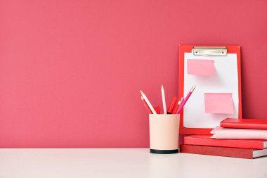 Renk duvarının yanında not defterleri ve kırtasiye malzemesi olan şık bir iş yeri