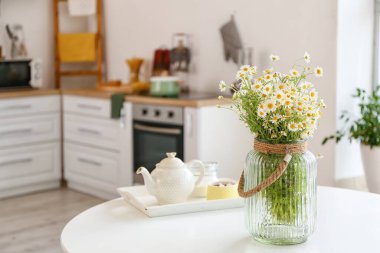 Mutfaktaki masada papatya çayı olan vazo.