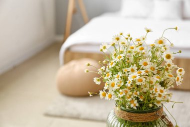 Yatak odasında papatya çayı olan vazo, yakın plan.