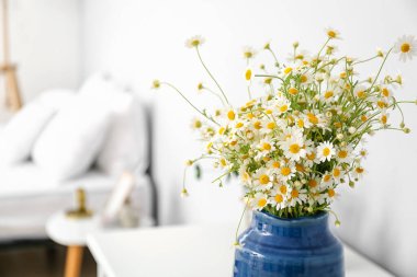 Yatak odasındaki masada papatya çayı olan vazo, yakın plan.