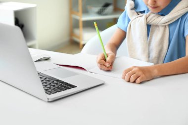 Küçük liseli kız evde deftere yazıyor.